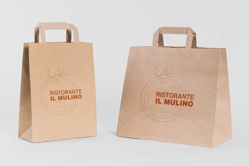 Due borse di carta marrone con manici, con il logo del Ristorante Il Mulino e un semplice disegno circolare con foglie.