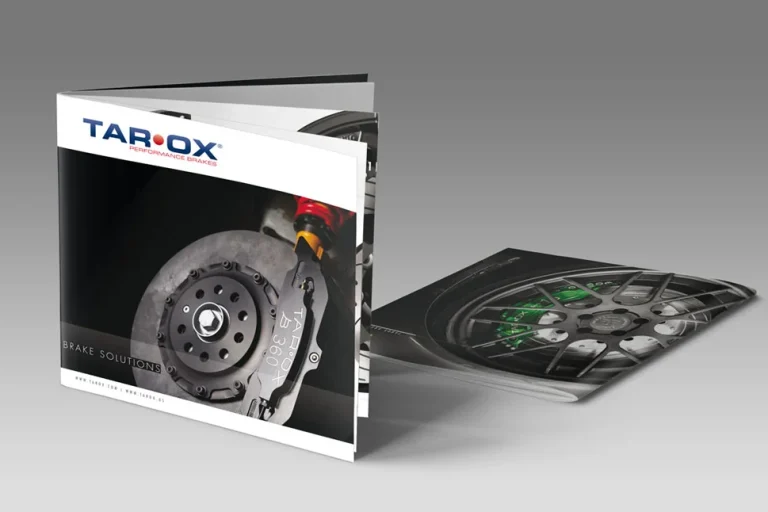 Sono esposte due brochure automobilistiche: una è aperta e mostra l'immagine di un disco dei freni sulla copertina, mentre l'altra è distesa e rivela parte della ruota di un'auto e del sistema frenante al suo interno.