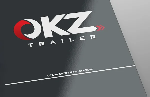 brochure plastificazione lucida Copertina nera con logo OKZ TRAILER in bianco e rosso, con semicerchio e freccia rossi, e sito web www.okztrailer.com in basso.