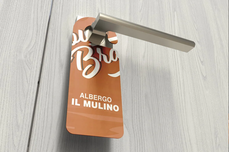 Una maniglia con un'insegna marrone dell'Albergo Il Mulino, attaccata a una porta di legno chiaro.