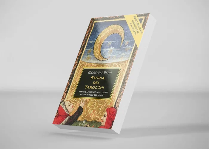 Un libro intitolato Storia dei Tarocchi di Giordano Berti presenta una copertina illustrata con una mezzaluna, figure medievali colorate e un riquadro del titolo nero bordato d'oro. Il libro è inclinato su uno sfondo semplice.