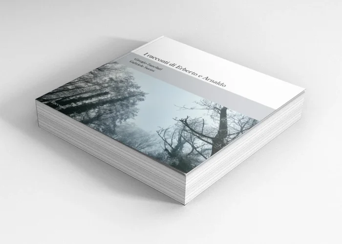 Una pila di libri con una copertina che mostra alberi senza foglie contro un cielo nuvoloso. Il titolo in italiano recita I racconti di Erberto e Arnaldo con testo aggiuntivo in basso, su uno sfondo pulito e minimalista.