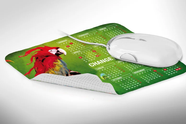 Un mouse bianco per computer poggia su un tappetino verde con un calendario e una grafica colorata a forma di pappagallo: un gadget promozionale perfetto per ravvivare qualsiasi spazio di lavoro.