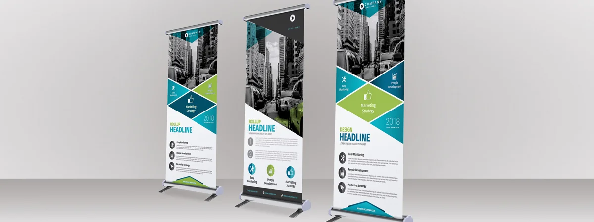 Tre banner roll-up verticali con disegni geometrici e contenuti di marketing aziendale visualizzati su uno sfondo chiaro.
