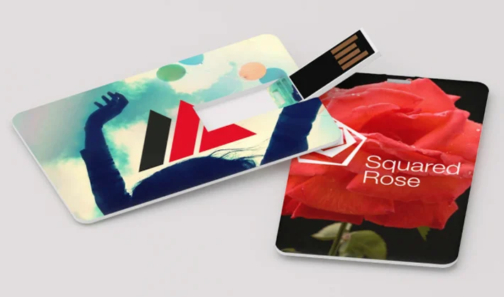 Due chiavette USB rettangolari con stampe personalizzate, una raffigurante una silhouette e forme astratte, l'altra una rosa rossa con il testo Squared Rose.