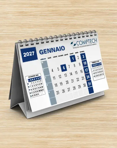 Un calendario da tavolo del 2027 aperto a gennaio, con date in italiano, una piccola anteprima del dicembre 2026 e i contatti dell'azienda in basso, appoggiato su una superficie di legno.